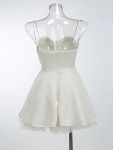 Back view of an ivory white spaghetti strap tutu dress with a zipper and mesh hem.