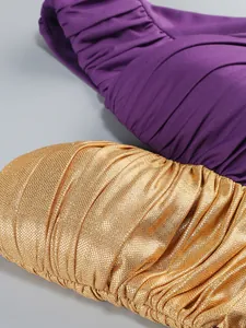 Close-up detail of one-shoulder evening dress showing purple pleats and gold metallic fabric.