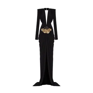 Elegant black long-sleeved evening gown with deep V-neck and golden moth brooch detail