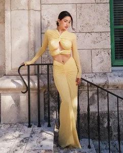 Elegant yellow two-piece set featuring long-sleeved knot crop top and ruched maxi skirt