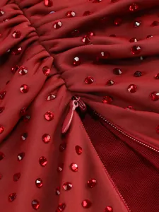 Close-up detail view of red evening dress fabric with hot-drilled rhinestones and zipper
