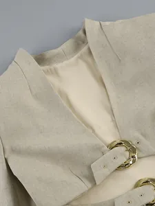 Close-up view of a high-quality beige linen-textured top with elegant gold buckle detail