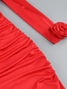 Close-up detail of a red ruched bodycon dress featuring a 3D fabric rose on the sleeve.
