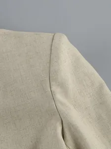 Detailed view of the textured linen fabric and shoulder seam on a beige long sleeve top