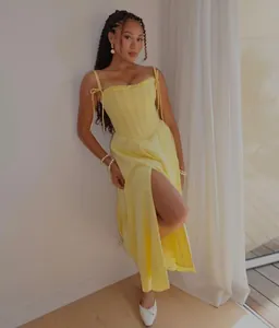 Modella con un elegante abito lungo a corsetto giallo con spacco alto e spalline