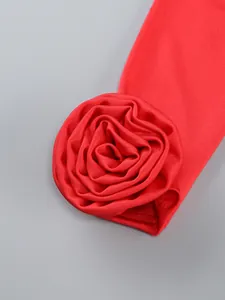 Macro view showing the intricate 3D fabric rose flower detail on a red formal dress