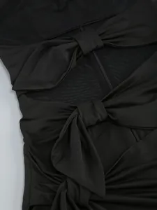 Close-up detail of a black mesh dress with elegant bow accents and a visible zipper.