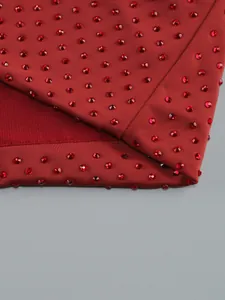 Macro view showing the sparkling red rhinestone details on elegant wine red dress fabric