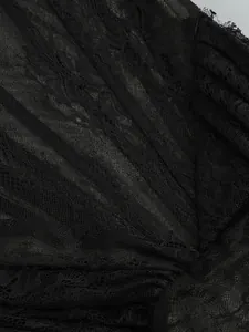 Macro detail view of black floral lace fabric with sheer texture and elegant pleats
