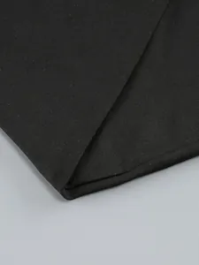 Close-up of the high-quality black ribbed fabric and precision stitching on the dress hem.