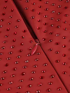 Close-up of invisible zipper and red rhinestones on elegant red dress fabric