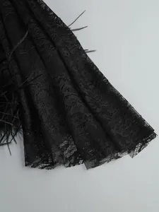 Detailed macro shot of intricate black lace textile and delicate feather accents on dress