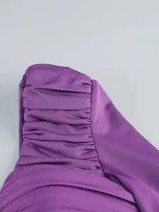 Macro view showing the intricate ruched pleats on the strap of a purple one-shoulder evening gown.