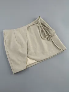 Macro detail of high-quality beige linen wrap mini skirt featuring an irregular tie-up design