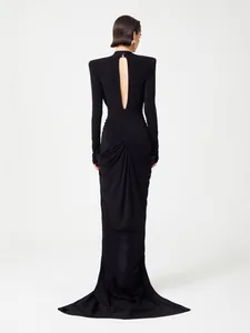 Elegant black long sleeve backless maxi dress with fishtail hem and padded shoulders