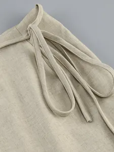 Detailed view of beige linen-textured fabric with lace-up tie detail on the waistband
