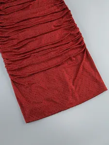Close-up of red evening dress featuring dense rhinestone embellishments and ruching.