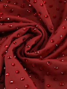 Detailed macro view of burgundy fabric with sparkling red rhinestone embellishments