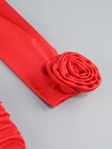 Close-up detail of a large 3D rose design and elegant ruched fabric on a red formal dress