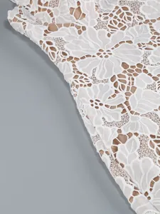 Close-up of intricate white floral lace embroidery on a bodycon evening dress fabric