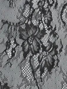 Macro view of delicate black floral lace fabric with intricate mesh patterns for dresses