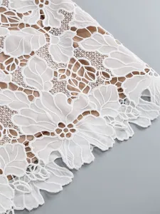 Detailed macro view of white floral lace embroidery with nude lining on formal dress