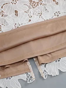 Detail shot of white floral lace overlay and tan lining on an elegant dress