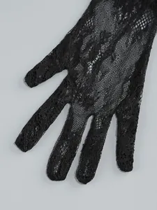 Detailed close-up showing the intricate floral lace texture of black bridal gloves