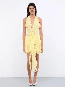 Detail shot of a pale yellow ruffled halter dress with a 3D floral waist ornament.