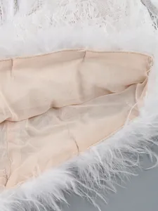 Macro detail shot showing the white lace texture and feather trim on an elegant evening dress