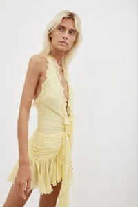 Detail view of a sexy yellow ruffled halter neck dress with ruched fabric texture
