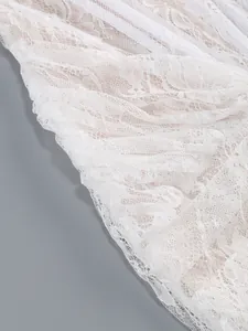 Detail of elegant white lace dress showing intricate mesh and floral embroidery texture