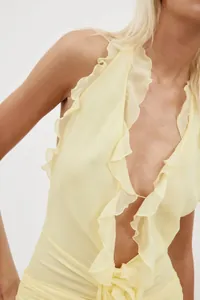 Detailed view of a pale yellow halter dress featuring elegant cascading ruffles.