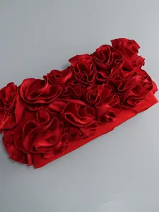 Dettaglio ravvicinato di un elegante abito a fascia rosso con fiori 3D in raso lucido.