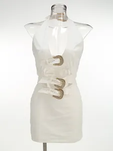 Detail of white halter dress featuring sexy hollow-out design and rhinestone buckles.