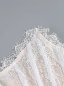 Close-up detail showing white floral lace with delicate eyelash trim on a corset top