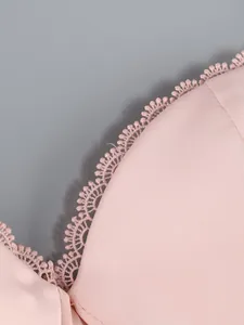 Detailed macro view of the delicate scalloped lace trim on a pink satin dress neckline