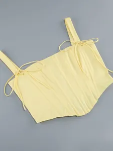 Dettaglio ravvicinato di un corsetto giallo con stecche verticali e spalline a fiocco
