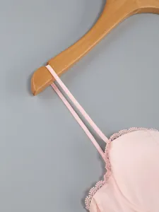 Macro view showing the fine lace trim and thin spaghetti straps of a pink summer dress