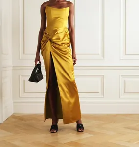 Detailed view of yellow satin strapless evening gown with a high slit and knot detail.