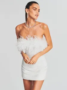 Primer plano de un vestido palabra de honor blanco con lentejuelas y plumas elegantes.