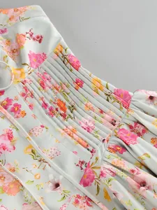 Dettaglio della vita a pieghe su un abito lungo floreale con scollo all'americana e fiori rosa