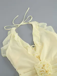 Detail shot of a light yellow halter neck dress with ruffles and a 3D fabric flower