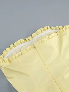 Dettaglio dello scollo a balze e cerniera invisibile sul vestito a fascia giallo