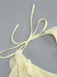 Close-up of pale yellow halter dress featuring delicate ruffles and neck tie detail.