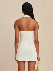 Detailed back view of an elegant white halter mini dress with gold metal buckle ornament