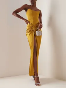 Full view of a mustard yellow strapless maxi dress with a front knot and high slit detail.
