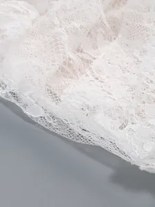 Detailed macro shot of elegant white floral lace fabric on a luxury evening dress
