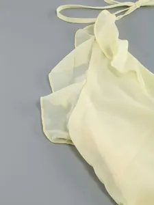 Close-up of pale yellow chiffon dress featuring delicate ruffle detailing and tie-neck