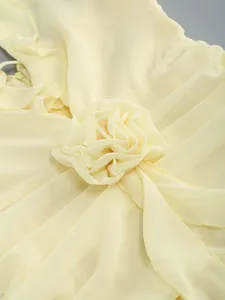 Detailed view of the 3D flower and ruffled pleats on this elegant yellow chiffon evening gown